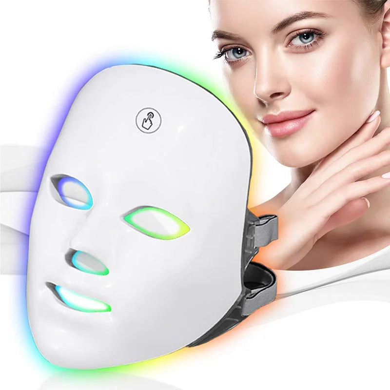 A woman is applying a white LED facial therapy mask to her face, showing various colored lights on the mask.