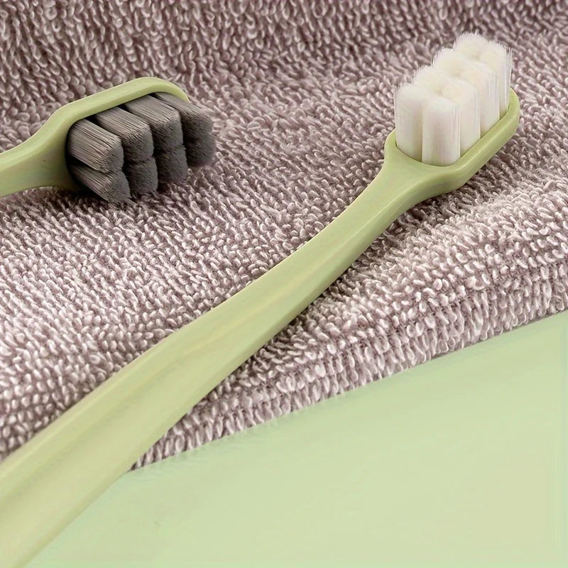 Une brosse à dents vert clair avec des poils blancs repose sur une serviette grise.