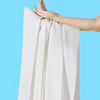 A hand is holding a white disposable towel with a textured surface against a light blue background.