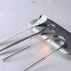 A set of stainless steel U-shaped tongue scrapers resting on a gray surface.