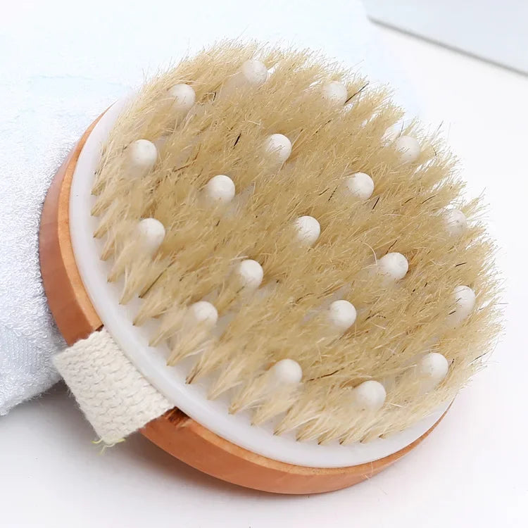 A natural wooden body brush with light brown bristles and white balls for dry brushing and exfoliation.