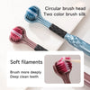 Un set de deux brosses à dents en soie multicolores avec des têtes circulaires, montées à côté d'une surface blanche.