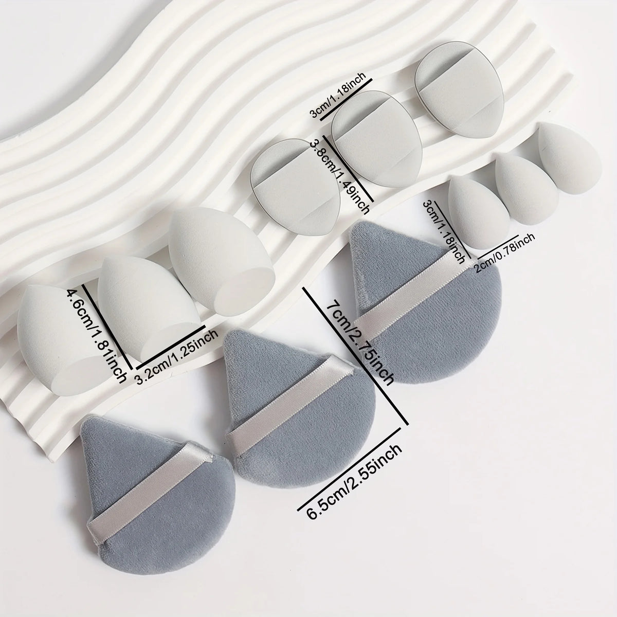A set of twelve white and gray makeup sponges arranged diagonally on a white background.