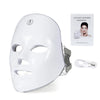 A white LED facial therapy mask with a silicone strap and accompanying power cord.