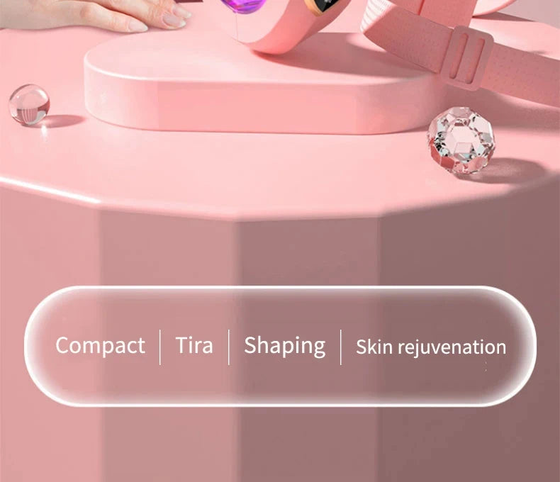 Pinker elektrischer Gesichts-Massager mit rosa Band neben Kosmetikperlen auf rosa Oberfläche.