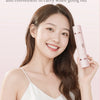 A smiling woman holds a pink electric body and hair removal razor while wearing a white top.