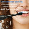 Primer plano de la boca de una persona mostrando un cepillo de dientes vibratorio negro siendo usado para limpiar los dientes