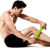 A muscular man is using a bright green manual muscle roller stick for deep tissue massage on his leg.