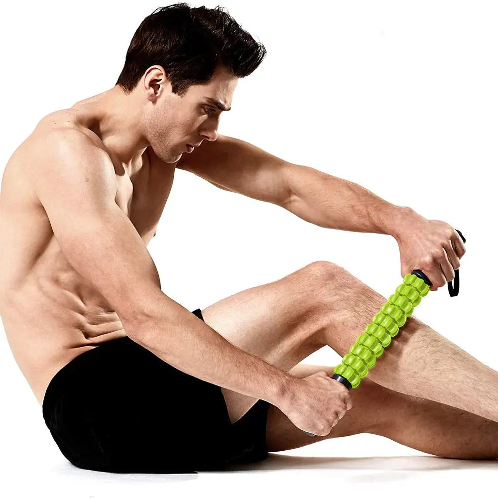 A muscular man is using a bright green manual muscle roller stick for deep tissue massage on his leg.