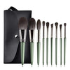 A set of professional makeup brushes in a dark olive green color displayed on a black background.