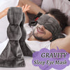 A man is wearing a gray gravity sleep eye mask while relaxing, with a pair of matching eye masks nearby.
