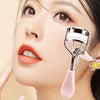 Gros plan d'une femme appliquant un recourbe-cils rose professionnel avec un peigne sur son œil.