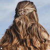 A woman's long, wavy blonde hair is styled with a braided updo and adorned with a leopard print oval flat hair clip.