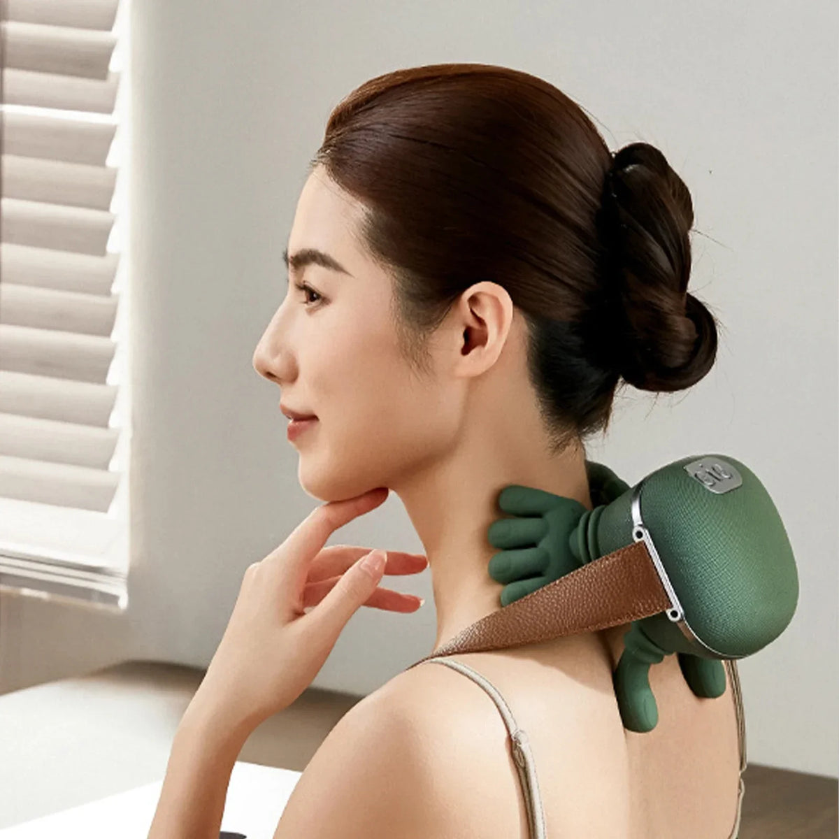 A woman is using a green deep tissue shiatsu massager for neck and shoulder relief on her neck.