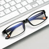 A pair of black-framed reading glasses with blue and orange accents resting on a white keyboard.