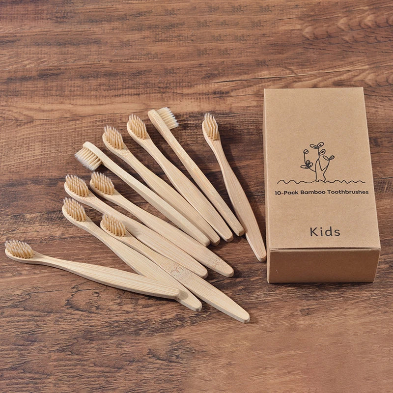Une boîte de dix brosses à dents en bambou pour enfants posée sur une surface en bois.