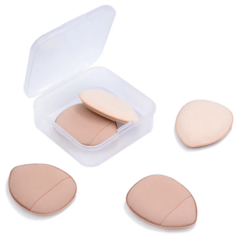 Un récipient transparent contenant plusieurs petits éponges de fond de teint rondes et beiges pour un maquillage précis.