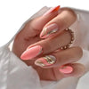 Close-up of a hand displaying press-on false nails with a pink and gold wavy French design.