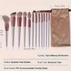 A set of 13 professional makeup brushes with synthetic fiber bristles and aluminum tubes displayed on a wooden stick.