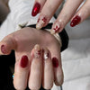 Une main montrant un ensemble de faux ongles à presser d'almond roses avec des accents floraux dorés.