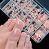 Una mano muestra una caja de prensa francesa de 120 piezas en uñas en tonos rosa y nude.