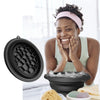 A woman is using a black silicone foldable ice bath bowl for a facial plunge, with ice and facial cleanser nearby.