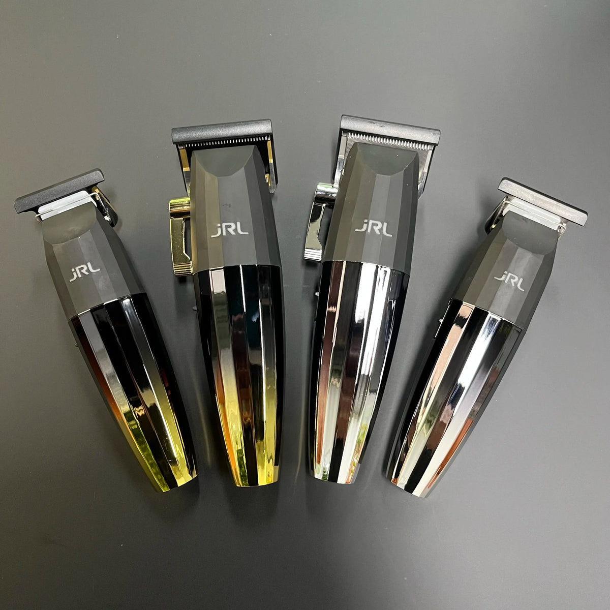 Ein Set von vier professionellen rotierenden Haarschneidern mit silbernen und goldenen Akzenten auf einer dunklen Oberfläche.