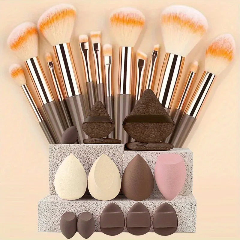A collection of makeup brushes and sponges in various shades of brown, pink, and orange displayed on a light background.