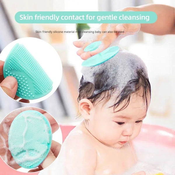 A baby is being gently cleansed with a light blue silicone facial cleansing brush in a bathtub.