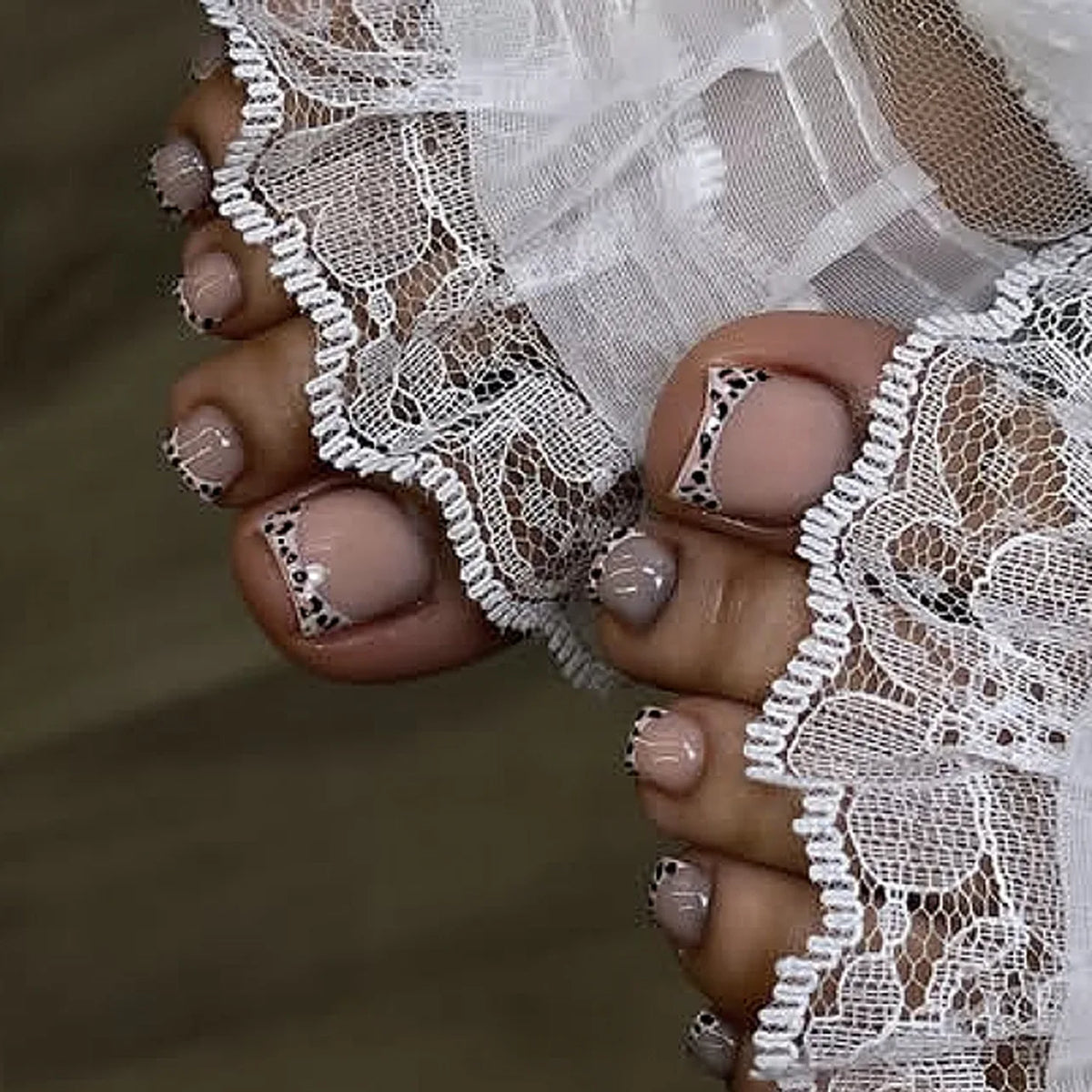 Close-up of hands with short square French press-on nails and sheer white lace fabric