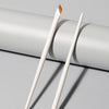 A pair of soft outline fine eyeliner blade brushes lying on a light gray surface.