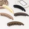 A collection of five banana-shaped hair clips in various shades of beige and brown for strong grip styling.