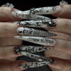 Gros plan d'une main présentant des kits de faux ongles en forme de fleur à amande, avec des motifs noir et blanc.