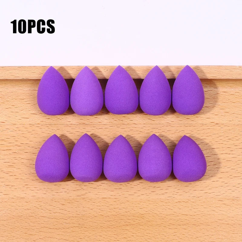 Ten purple makeup sponge puffs arranged in two rows on a wooden surface.
