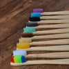 A wooden toothbrush set showing ten brushes of various colors arranged in a diagonal line.