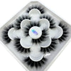 A white tray holds a cluster of black natural mink striped false eyelash extensions.