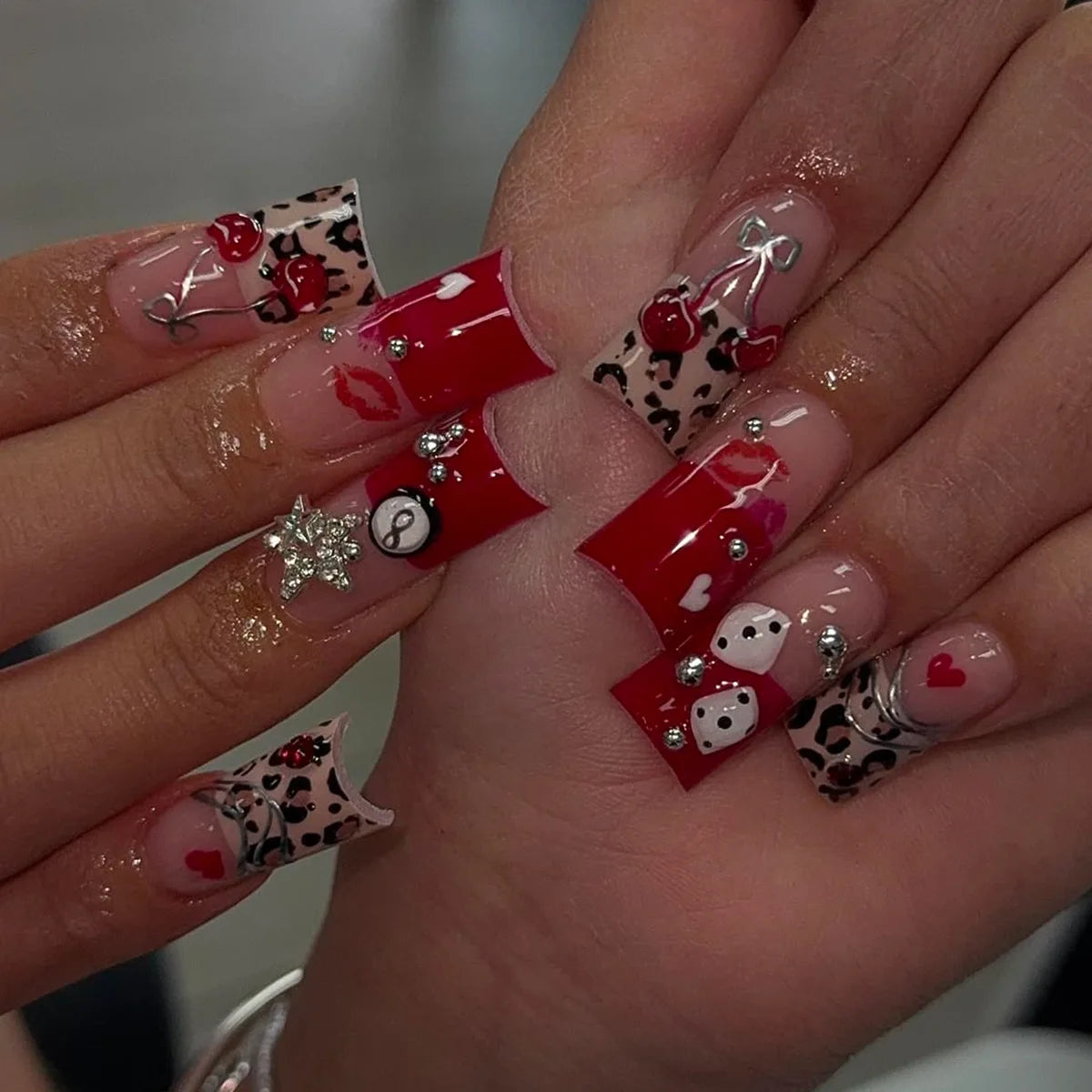 A close-up of a hand displaying Y2K sweet stars press-on nails with a black and white leopard print design.