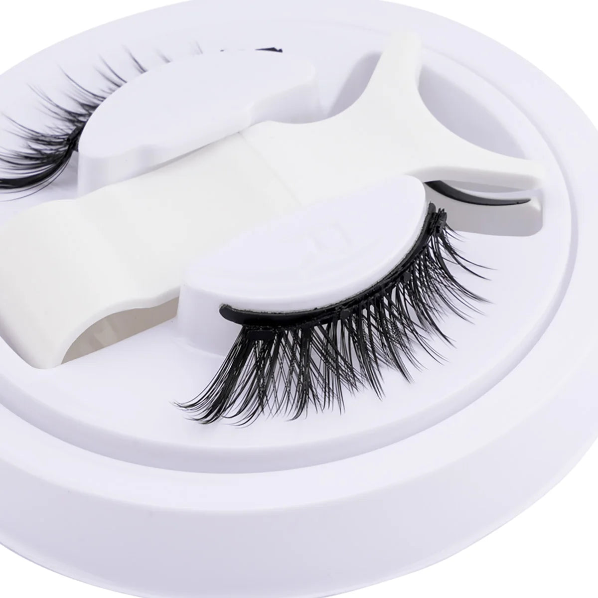 Un ensemble de faux cils magnétiques réutilisables blancs avec des pinces, présenté sur un fond blanc circulaire.