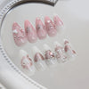 A set of 24 pink heart pearl press-on fake nails displayed on a white surface.