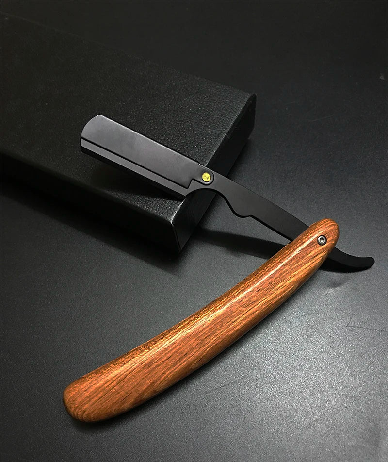 Mango de madera y hoja negra de una maquinilla de afeitar manual profesional sobre una superficie oscura.