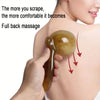 A hand applies a golden resin gua sha tool to the neck and shoulder area for massage.