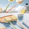 A long-handle loofah back scrubber with a soft mesh sponge in light green and peach tones is shown alongside a white towel an