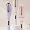Three automatic ceramic hair curlers in purple, yellow, and pink are displayed vertically on a white surface.