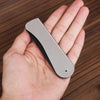 A hand holds a silver foldable anti-static steel comb for hair, beard, and wigs.