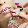 Des mains appliquent du vernis à ongles pailleté rose et or sur un doigt, avec un outil de sélection de strass visible à prox