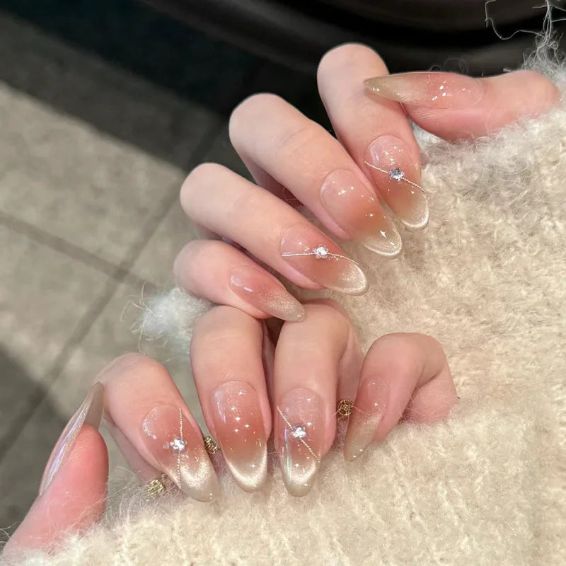 Gros plan d'une main montrant des ongles press-on à noisette française roses avec de petits accents scintillants.
