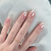A hand displaying pink flower almond press on nails on a white fabric background.