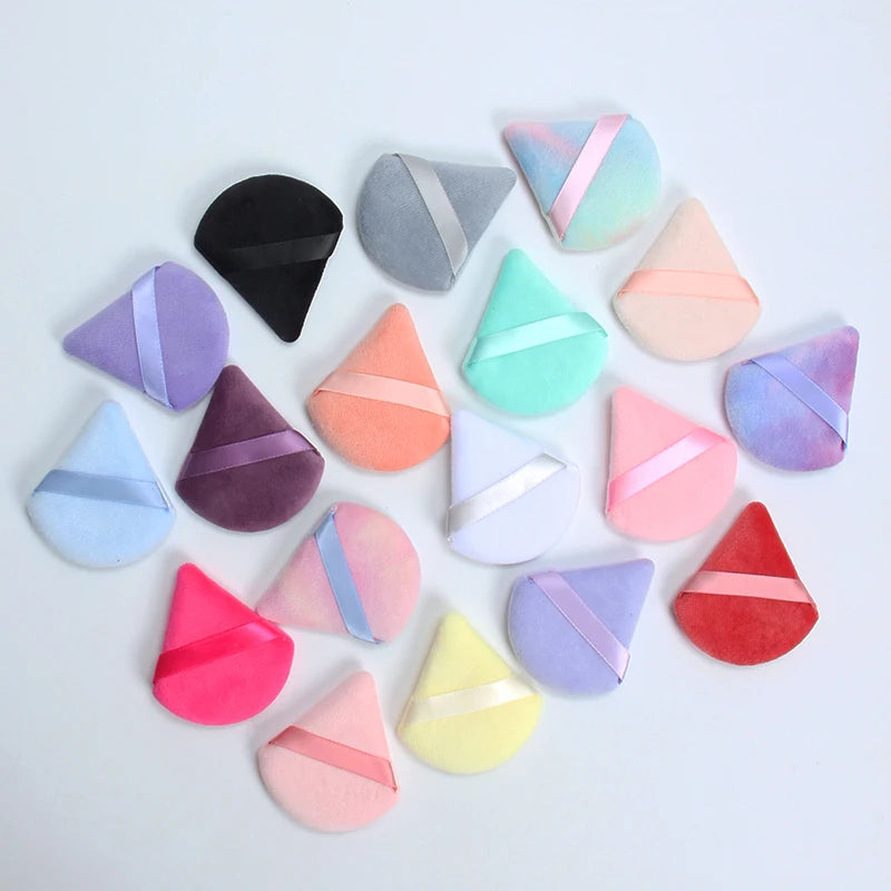 Une collection de six éponges de maquillage triangulaires dans diverses teintes pastel, incluant rose, violet, vert et orange
