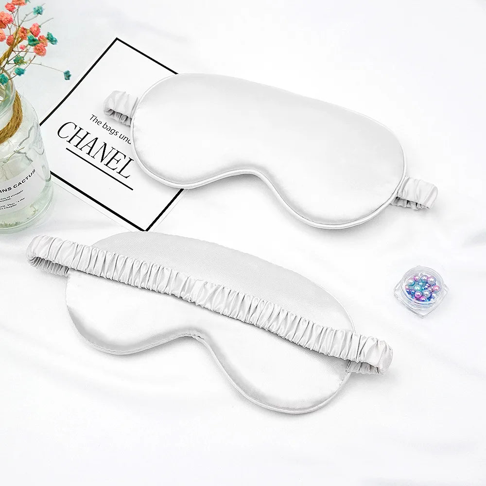 Masque de sommeil imitation soie blanche avec bord froncé sur fond blanc.
