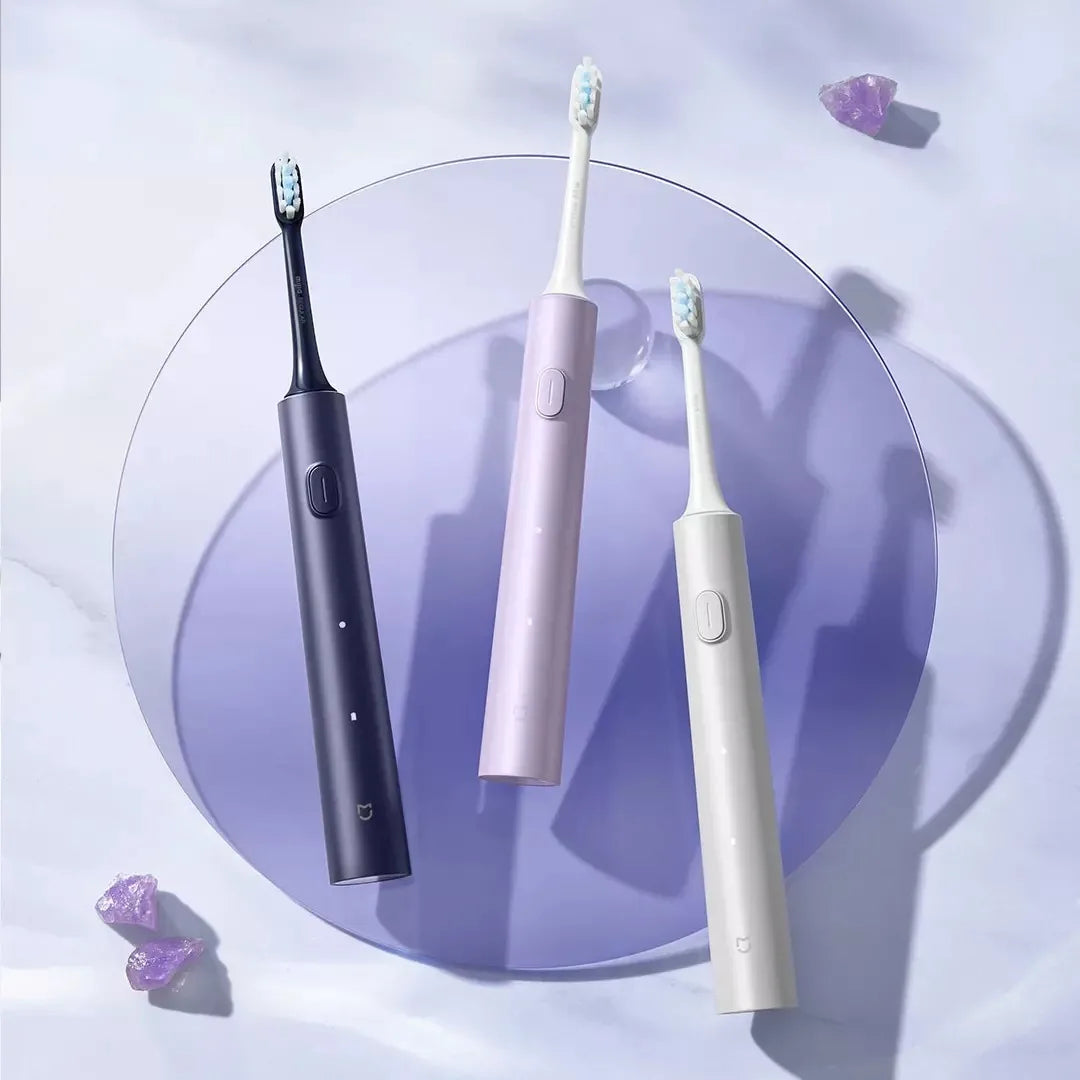Three sonic electric toothbrushes in black, lilac, and white are displayed on a purple plate.